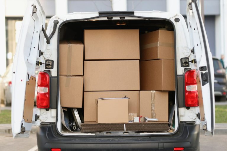 A van's back, filled with stacked cardboard boxes of various sizes.